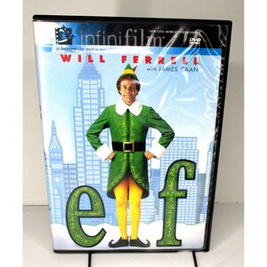 May include: DVD case for the movie "Elf" featuring Will Ferrell. The cover shows Ferrell in an elf costume with a green jacket, yellow tights, and the title "Elf" in large green letters. The background depicts a city skyline.
