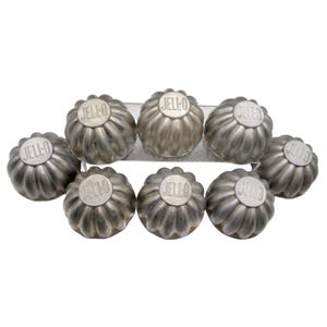 May include: A set of eight silver-toned metal Jell-O molds, each featuring a fluted, scalloped design and the embossed text JELL-O on the top center. The molds are arranged in a cluster, showcasing their metallic finish and uniform shape.