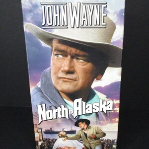 May include: A VHS tape case featuring John Wayne wearing a cowboy hat. The title of the film is "North to Alaska". The image shows a scene from the film with John Wayne and another man.