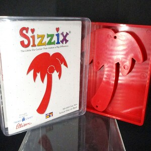 May include: A red plastic palm tree die-cutter in a clear plastic case. The case has the Sizzix logo and the text "The Little Die-Cutter That Makes a Big Difference".