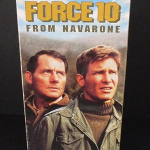 May include: A VHS tape case featuring the movie "Force 10 from Navarone" starring Robert Shaw and Harrison Ford. The case is yellow and black with a photo of the two actors on the front.