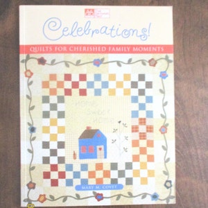 Könnte beinhalten: Ein Buch mit dem Titel "Celebrations! Quilts for Cherished Family Moments" von Mary M. Covey. Der Umschlag zeigt ein farbenfrohes Quiltmuster mit einem Haus in der Mitte und den Worten "Home Sweet Home" darüber.