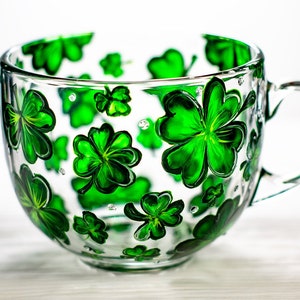Hand painted shamrock mug with green four leaf clovers on clear glass.