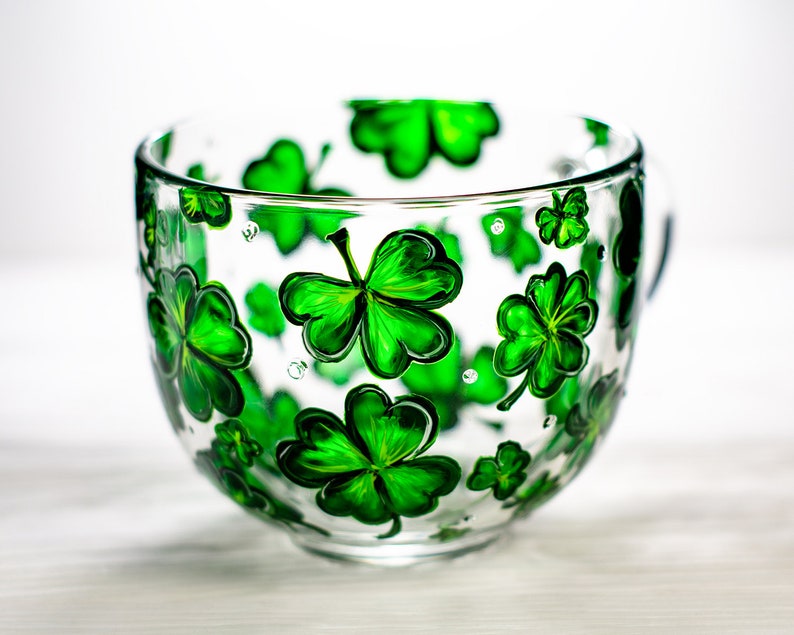 Personalized shamrock mug featuring green clovers around a transparent glass cup.