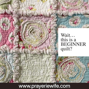 May include: Close-up of a handmade quilt with a patchwork design. The quilt features squares in shades of pink, blue, and white, adorned with floral patterns and ruffled edges. The text "Wait... this is a BEGINNER quilt?" is visible.