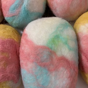 Könnte beinhalten: Nahaufnahme von mehreren bunten Woll-Trocknerbällen. Die Bälle bestehen aus gefilzter Wolle und haben verschiedene Farben, darunter Rosa, Gelb, Blau und Weiß.
