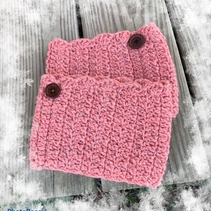 May include: Two pairs of pink crocheted leg warmers with brown buttons. The leg warmers are made with a textured stitch.