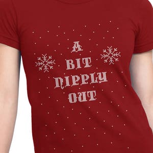 May include: Red t-shirt with a white snowflake design and the text "A Bit Dippy Out" in a pixelated font.