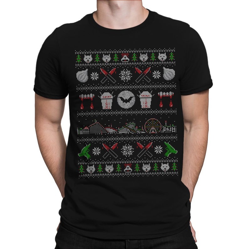 Puede incluir: Camiseta negra con un dise&ntilde;o de su&eacute;ter navide&ntilde;o blanco, rojo y verde con un murci&eacute;lago, ata&uacute;des, gotas de sangre, una monta&ntilde;a rusa y cuchillos.