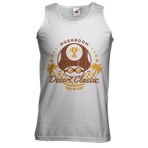 May include: White tank top with a brown graphic featuring a mushroom design, sunglasses, a trophy, palm trees, and the text "Mushroom Desert Classic 1992". The shirt is made of a soft material.