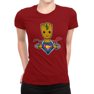 May include: Red t-shirt featuring a cartoon image of a superhero Groot, a character from the Guardians of the Galaxy, with a Superman logo on his chest.