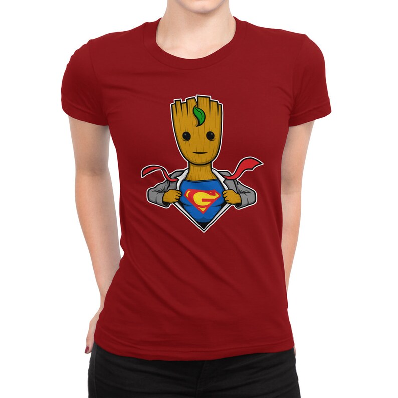May include: Red t-shirt featuring a cartoon image of a superhero Groot, a character from the Guardians of the Galaxy, with a Superman logo on his chest.