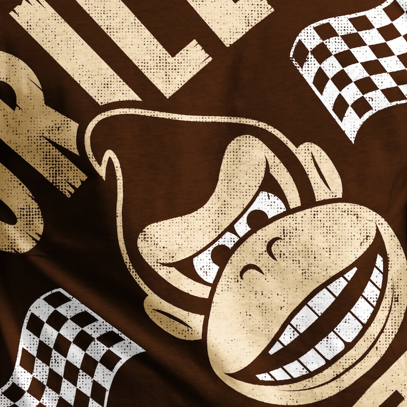 May include: A brown t-shirt with a vintage-style graphic of a grinning monkey wearing a racing helmet and a checkered flag. The text "DK" is visible in the background.
