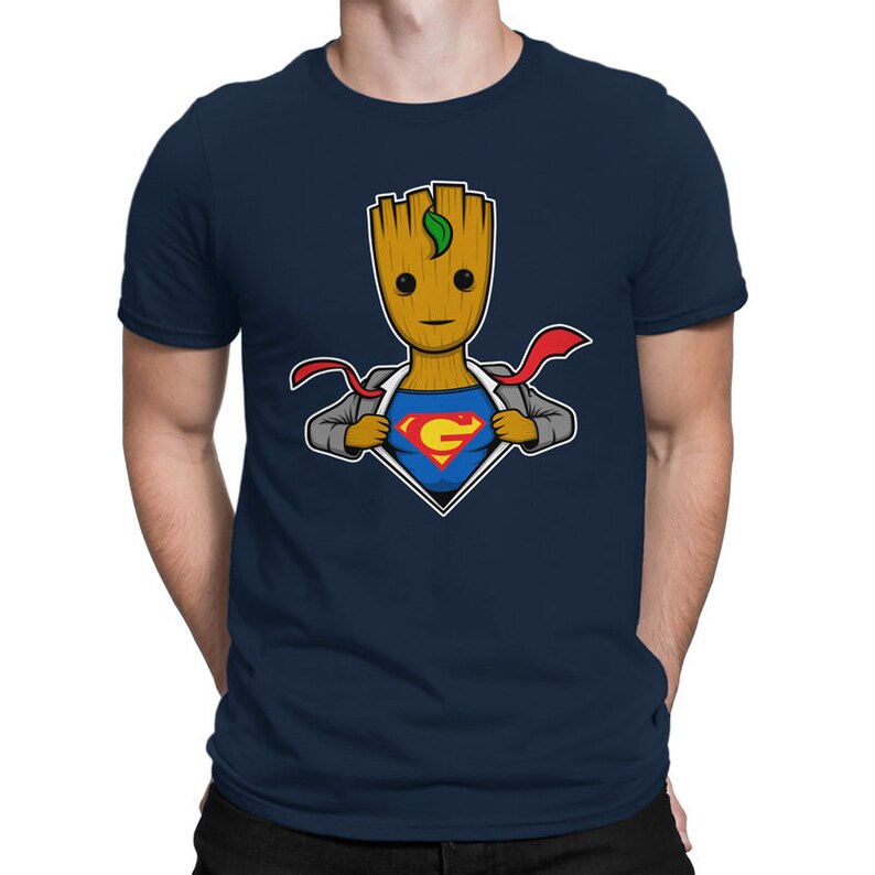 May include: A navy blue t-shirt with a cartoon image of a superhero Groot, a character from the Guardians of the Galaxy, wearing a Superman costume. The image shows Groot ripping open his shirt to reveal the Superman costume underneath.