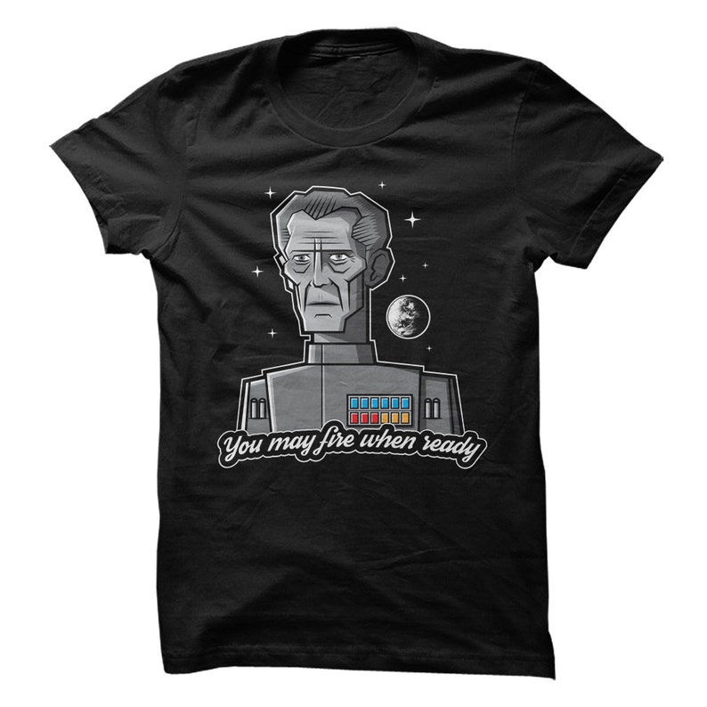 May include: A black t-shirt with a cartoon illustration of a man in a space uniform. The text "You may fire when ready" is printed below the illustration.
