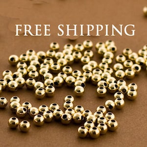 May include: A large quantity of gold-colored round beads, scattered on a brown surface.  FREE SHIPPING is written in white letters across the top of the image.