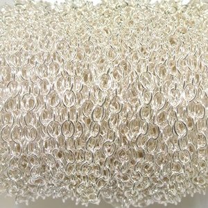 May include: A close-up of a silver chain, showing the individual links. The chain is coiled up and appears to be made of metal.