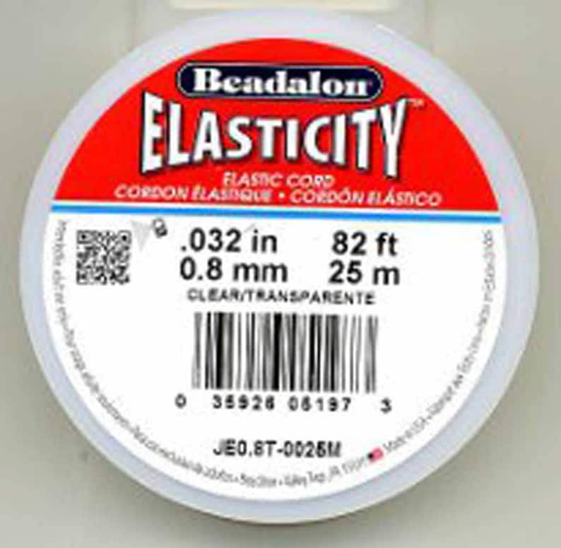 Puede incluir: Una bobina blanca de cord&oacute;n el&aacute;stico transparente con el texto "Beadalon ELASTICITY" en rojo y negro. La bobina tambi&eacute;n incluye el texto "FLASTIC CORD CORDON ELASTIQUE CORDON EL&Aacute;STICO" en negro. La bobina est&aacute; etiquetada con las medidas 0,032 pulgadas, 0,8 mm, 82 pies y 25 m.