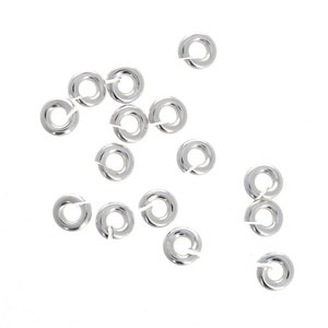 May include: A collection of silver jump rings, a type of jewelry finding used for connecting chains, cords, and other jewelry components.