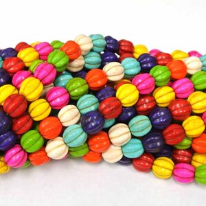 May include: A strand of colorful, round, and slightly flattened beads. The beads are made of turquoise and have a striped pattern. The beads are arranged in a loose pile.