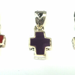 K&ouml;nnte beinhalten: Drei silberne Kreuzanh&auml;nger mit verschiedenen farbigen Einlagen. Das Kreuz links hat eine rote Einlage, das mittlere Kreuz eine violette Einlage und das Kreuz rechts eine wei&szlig;e Einlage.