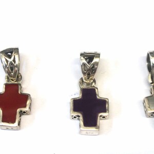 K&ouml;nnte beinhalten: Drei silberne Kreuzanh&auml;nger mit verschiedenen farbigen Einlagen. Das Kreuz links hat eine rote Einlage, das mittlere Kreuz eine violette Einlage und das Kreuz rechts eine wei&szlig;e Einlage.