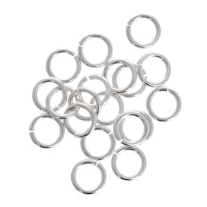 May include: A group of silver jump rings, a type of jewelry finding, arranged in a pile.