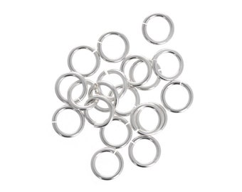 May include: A group of silver jump rings, a type of jewelry finding, arranged in a pile.