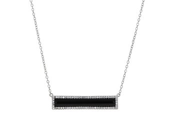 Può includere: Una collana con catena d'argento con un ciondolo a forma di barra nera. La barra è circondata da un bordo di piccole pietre trasparenti.