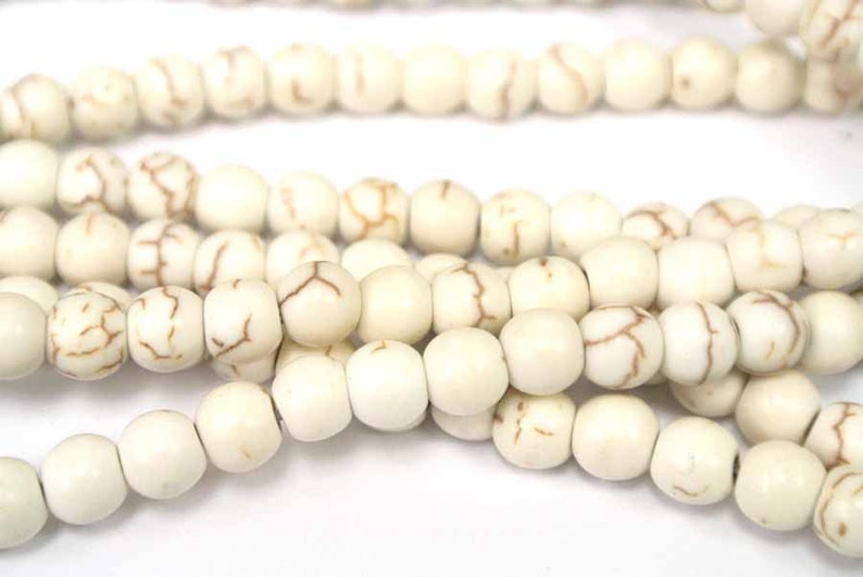May include: A strand of white howlite beads with brown veining. The beads are round and smooth.