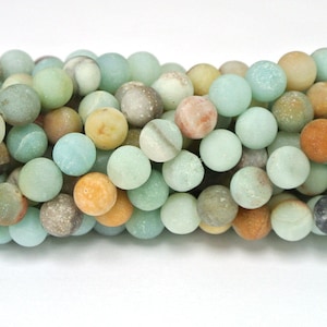 May include: A strand of round, smooth, green, brown, and yellow gemstone beads. The beads are approximately 8mm in diameter and have a matte finish.