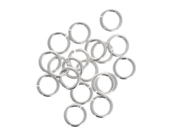 May include: A group of silver jump rings, a type of jewelry finding, arranged in a pile.