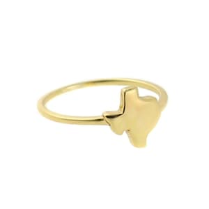 May include: A gold-coloured ring with a small, raised outline of the state of Texas.