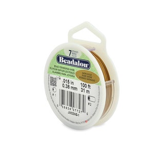 May include: A spool of 0.38 mm gold bead stringing wire. The spool is labelled "Beadalon" and has a 31 m length.
