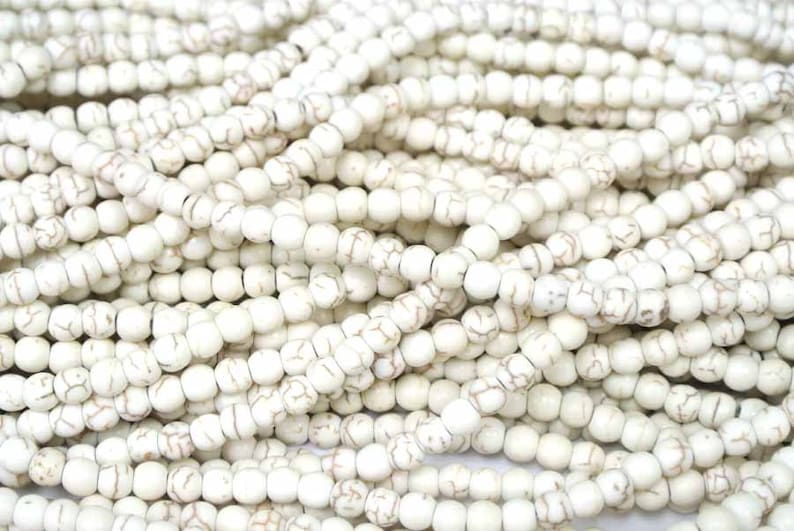 May include: A close-up of a pile of white howlite beads. The beads are round and have a smooth, polished finish. They are ideal for making jewellery or other crafts.