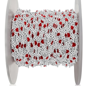 May include: A spool of silver chain with red heart-shaped beads. The chain is wound around a white spool.