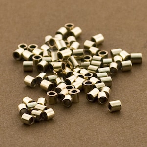 May include: A large pile of gold-colored metal crimp beads. The beads are small and round, with a hole in the center. They are used for jewelry making and other crafts.