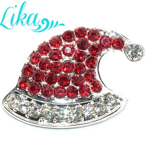 May include: A silver-toned Santa hat charm with red and clear rhinestones. The hat is shaped like a traditional Santa hat with a white fur trim.