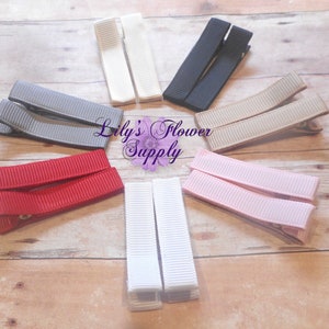 以下が含まれることがあります： 白、黒、グレー、赤、ピンク、ベージュなど、さまざまな色のヘアクリップ10個セット。クリップはグログランリボン製で、背面に金属製のクリップが付いています。  Lily's Flower Supply.