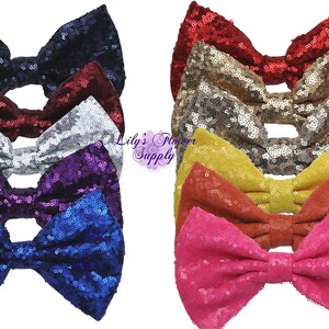 May include: Assortment of ten sequined bow hair clips in various colors, including black, red, silver, purple, blue, gold, yellow, orange, pink, and fuchsia.