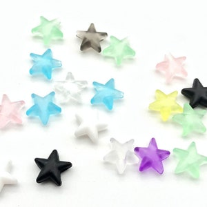 May include: Assortment of star-shaped beads in various colors, including light blue, pink, yellow, purple, green, white, black, and gray. The beads are made of plastic and have a frosted finish.