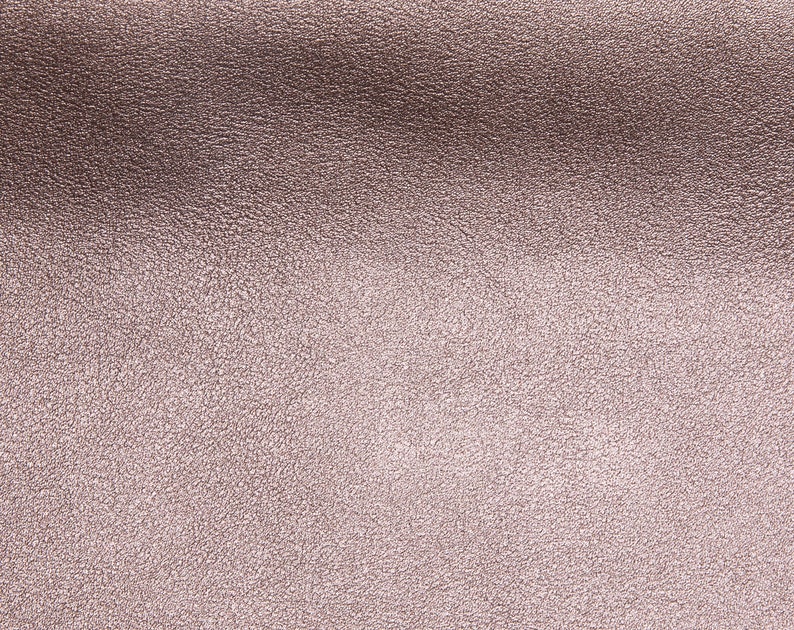 May include: A close-up of a textured, metallic surface with a subtle, rose gold sheen.