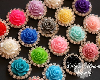 May include: Assortment of 15 colorful rhinestone-embellished flower embellishments. Each flower is a different color, including pink, blue, green, white, yellow, red, and purple. The flowers are surrounded by clear rhinestones.