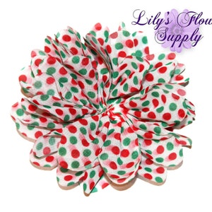 May include: A white fabric flower with red and green polka dots. The flower is made of multiple layers of fabric and has a ruffled appearance.