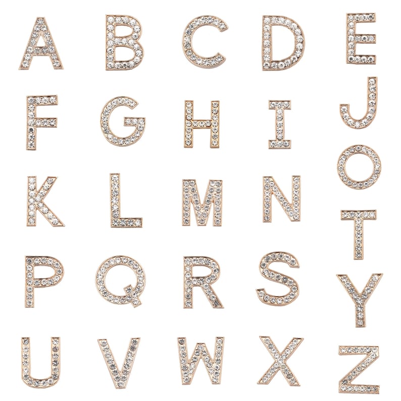 Puede incluir: Un conjunto de abalorios de letras del alfabeto de color dorado, cada letra est&aacute; incrustada con diamantes de imitaci&oacute;n transparentes. Las letras est&aacute;n dispuestas en orden alfab&eacute;tico.