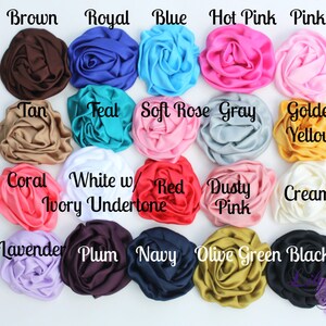 May include: A collection of 18 satin fabric flower embellishments in various colors, including brown, royal blue, teal, soft rose, gray, golden yellow, coral, white with ivory undertone, red, dusty pink, cream, lavender, plum, navy, olive green, and black.