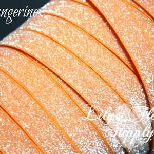 May include: Tangerine orange glitter ribbon. The ribbon is rolled up and has a shiny, sparkly finish.