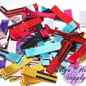 May include: A pile of colorful hair clips with a variety of colors including red, pink, yellow, blue, purple, and black. The clips are made of ribbon and have a metal clip.