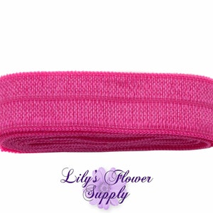 May include: A roll of pink elastic headband material. The material is textured and has a single line of stitching running across the width.