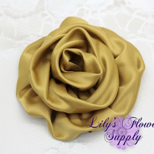 May include: A large, golden satin rose flower. The rose is made of fabric and has a soft, velvety texture.